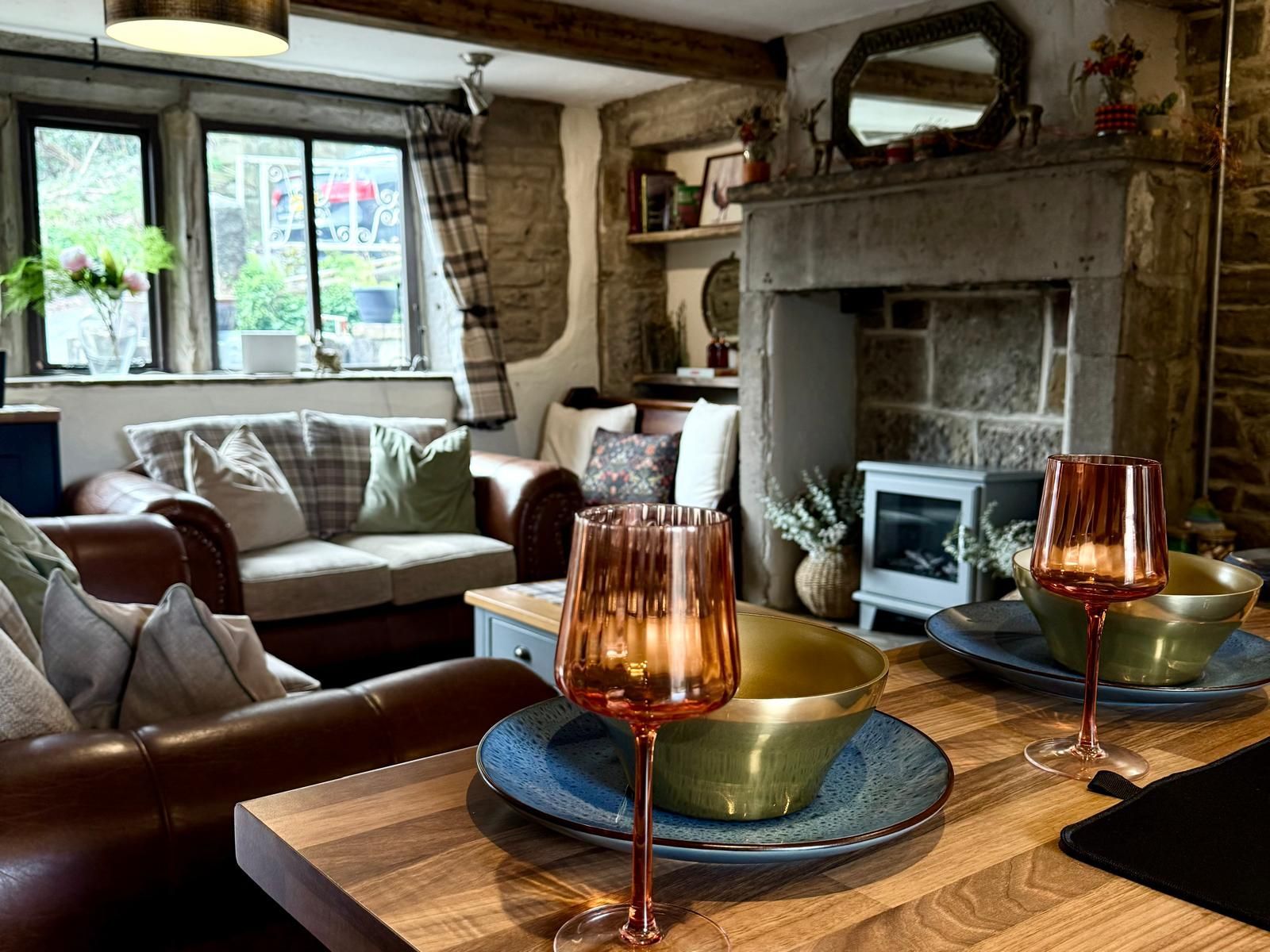 Cozy rustic living room with sofa, armchairs, stone fireplace, and set dining table with candles