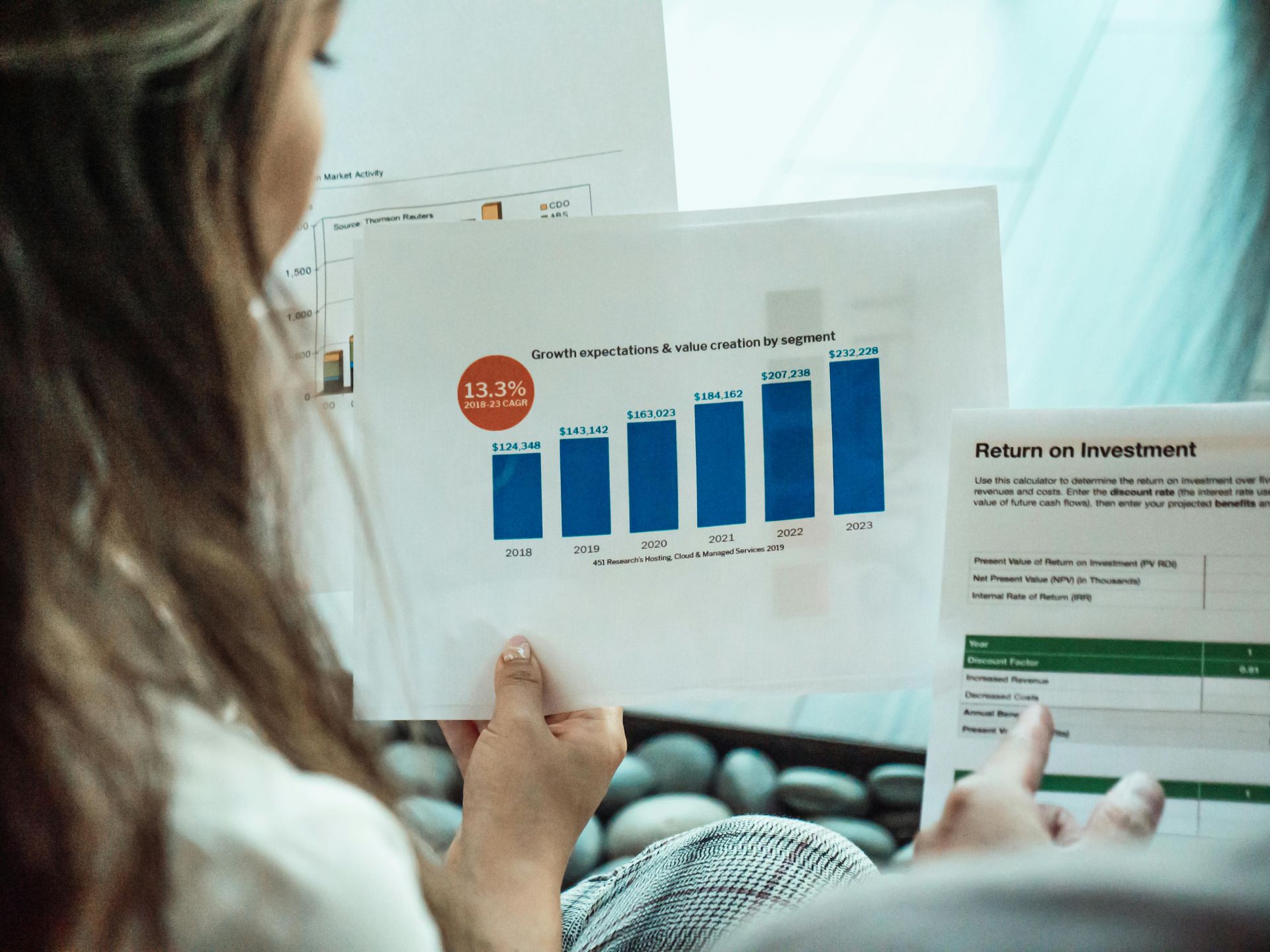 Person reviewing a financial graph with blue bars and 13.5% growth highlighted.