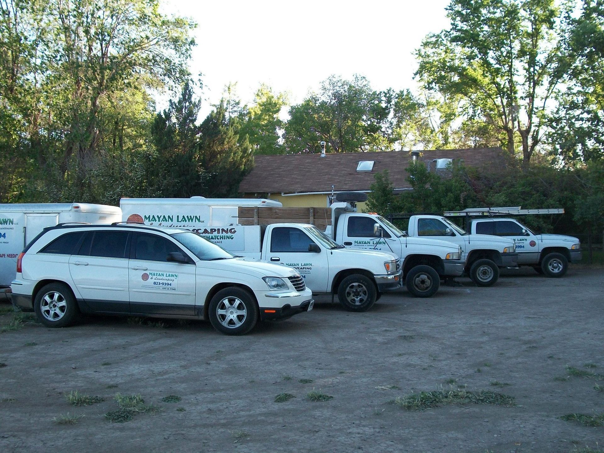 A row of white trucks parked in front of a house