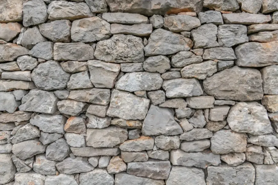 Close-up of a gray stone wall built from irregular stacked rocks