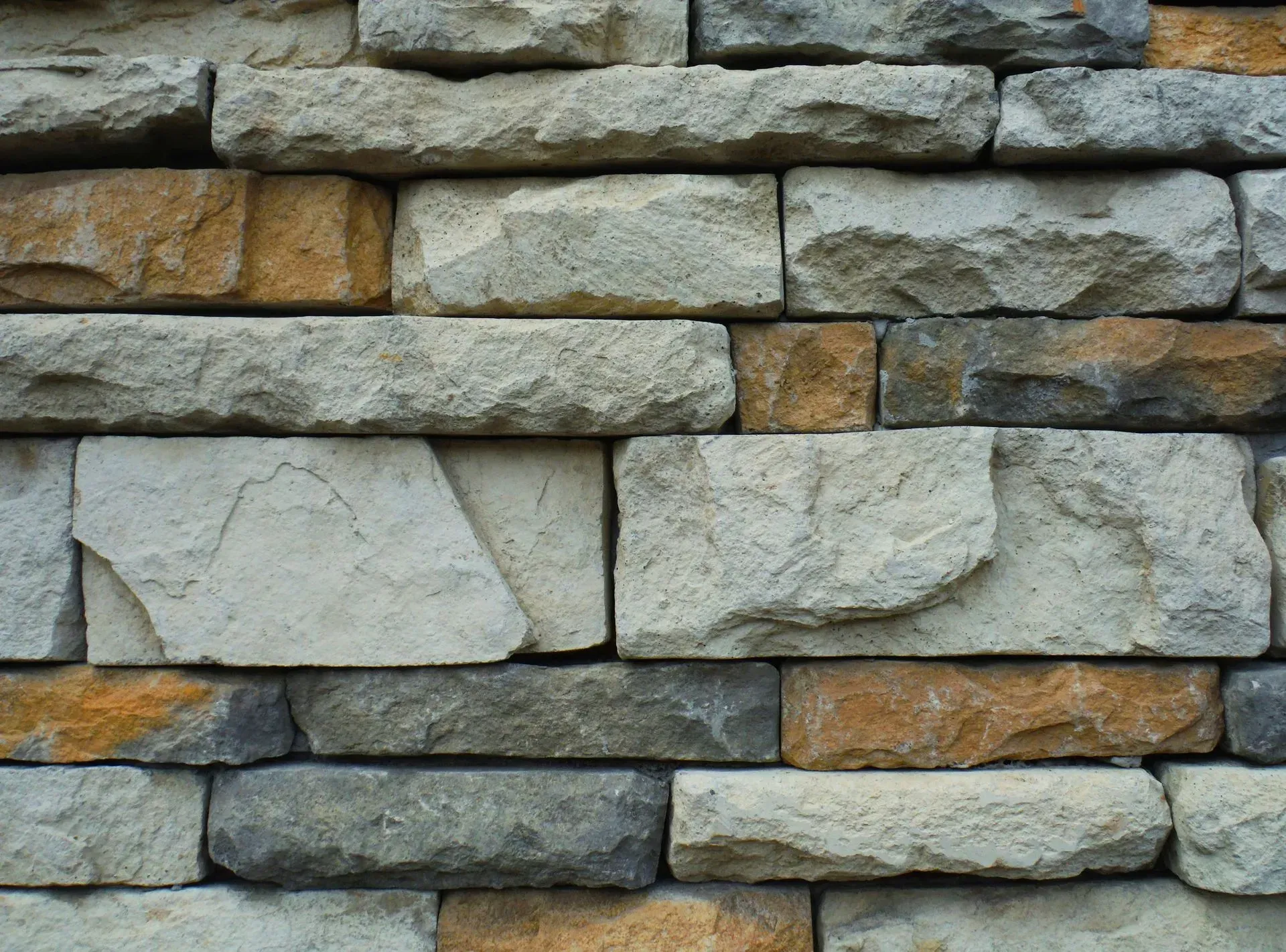Close-up of a stacked stone wall with gray, tan, and blue-gray blocks