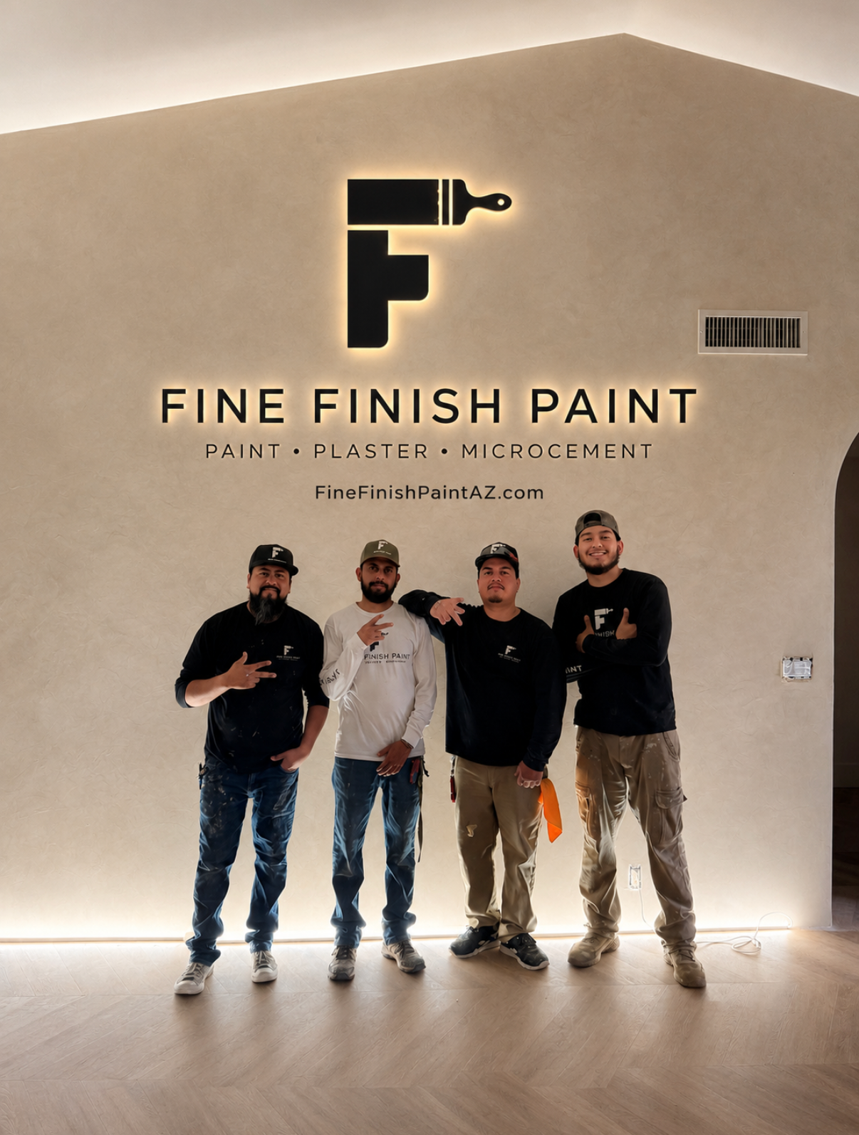 Four people standing in a bright showroom beneath a “Fine Finish Paint” sign and logo.