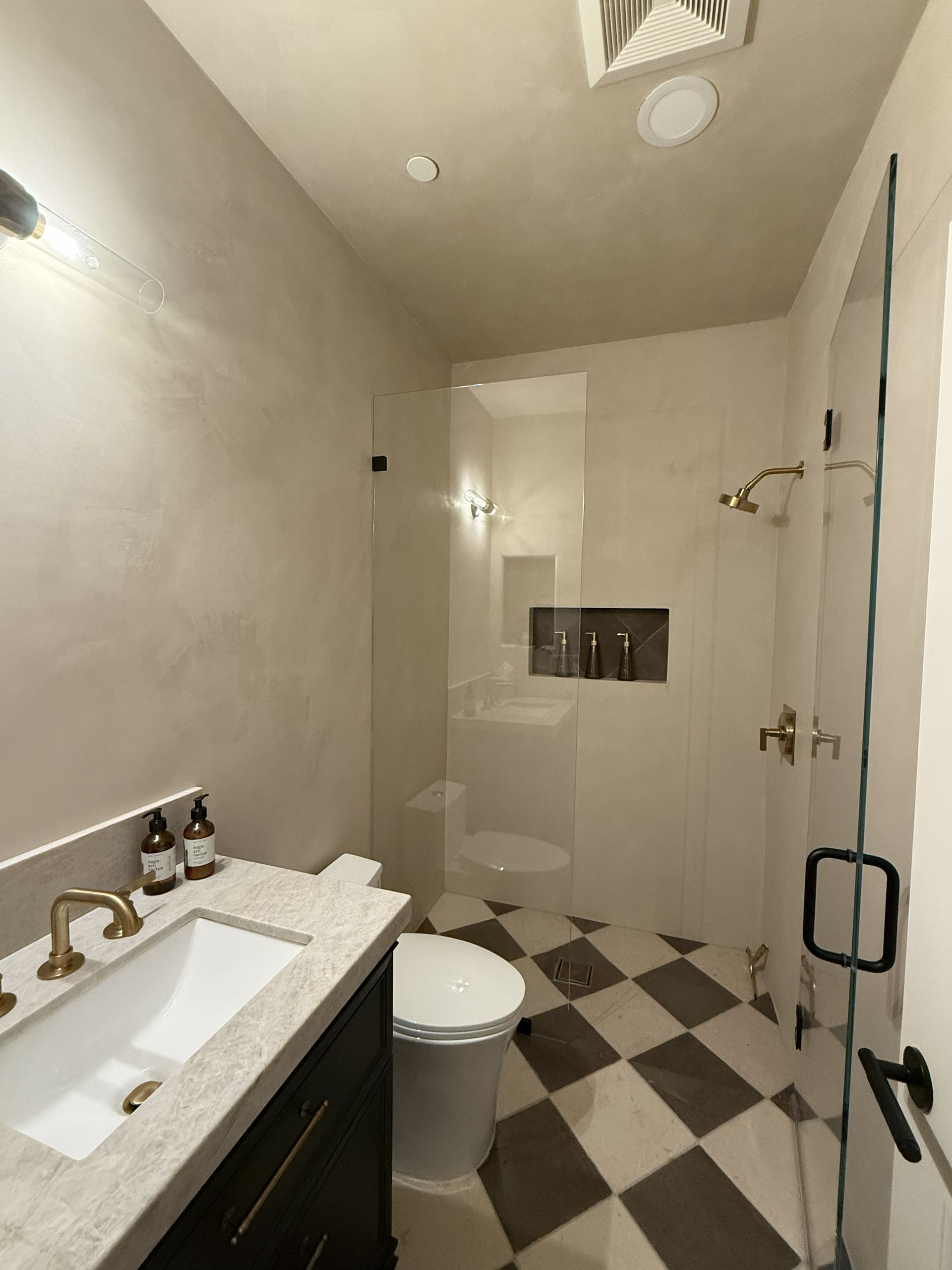 Small bathroom with a white sink, toilet, and tiled floor in black-and-white diamond pattern.