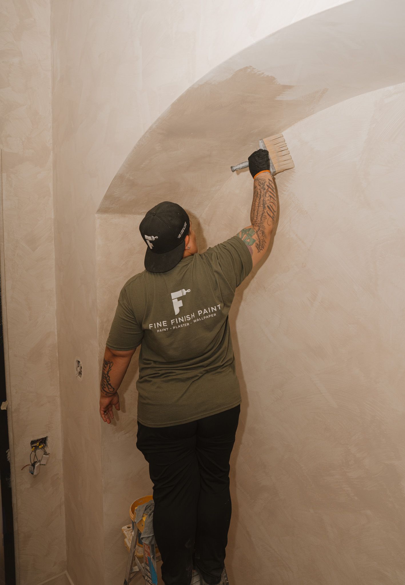 Person plastering a wall in a small room, smoothing a curved section with a trowel.