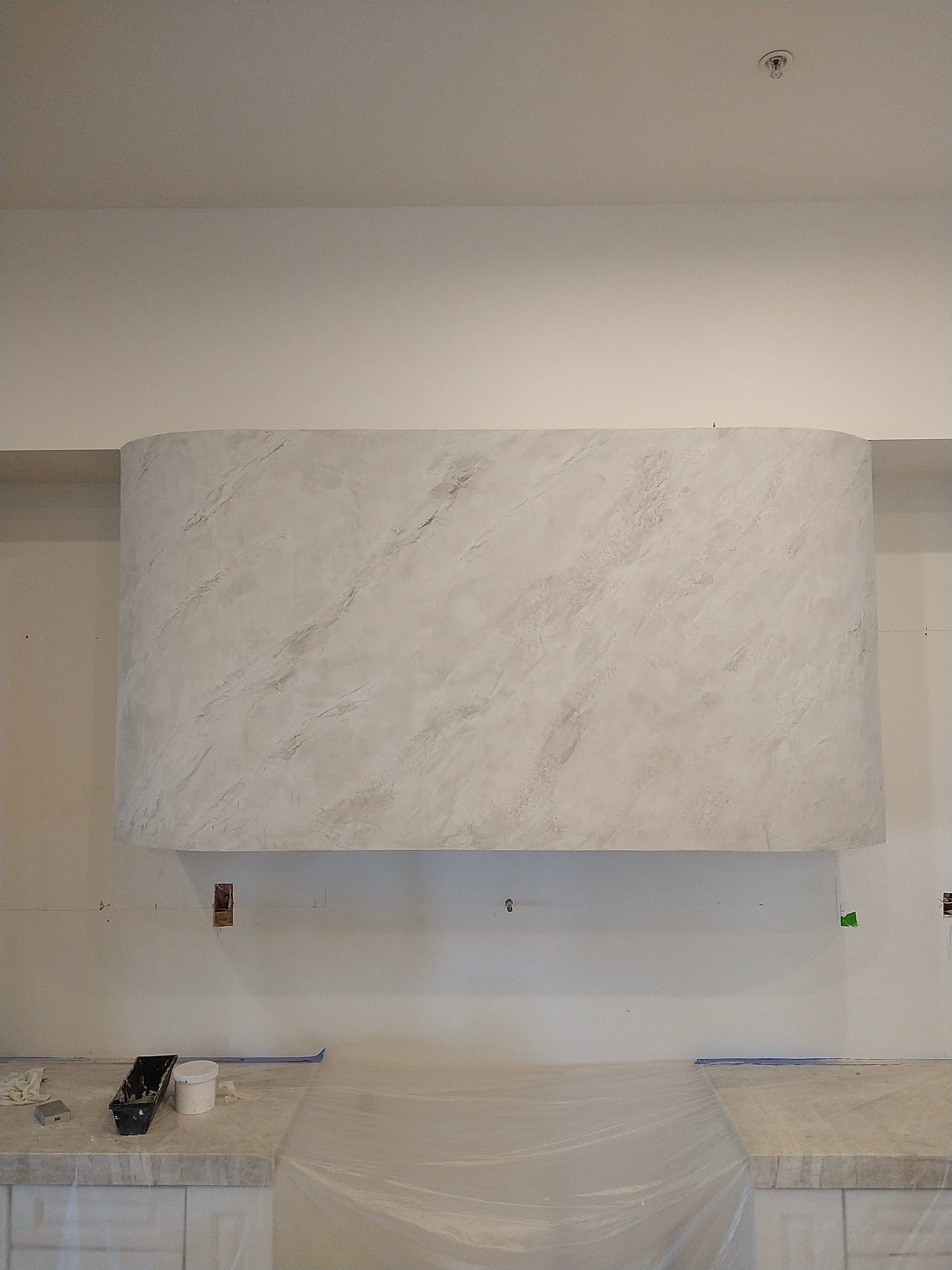White marble fireplace mantel above a clear plastic-covered surface in a minimalist room