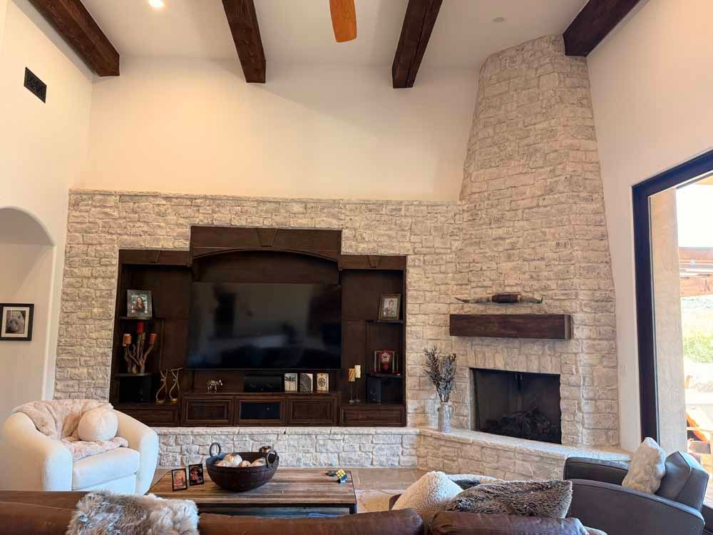 Spacious living room with stone fireplace, built-in shelves, vaulted ceiling, and light-colored sofas
