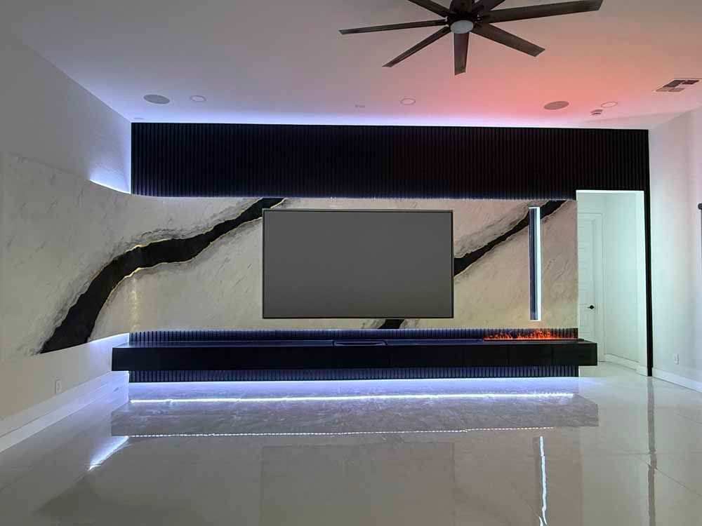 Modern minimalist lobby with curved stone wall, black bench, ceiling fan, and pink-blue ambient lighting