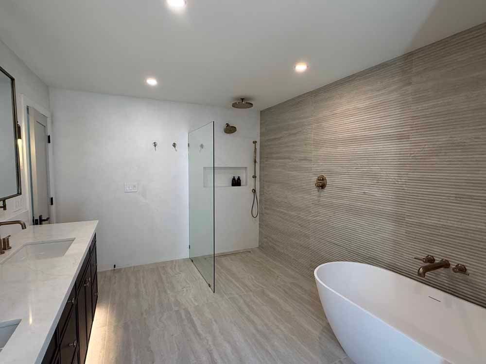 Modern bathroom with double vanity, freestanding tub, glass shower, and wood-textured accent wall