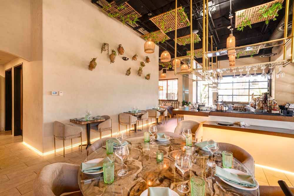 Elegant restaurant dining area with set table, warm lighting, and open kitchen bar