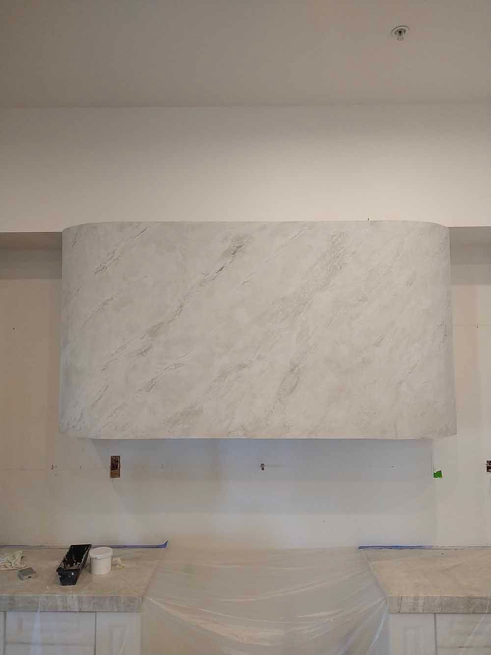 Modern kitchen with white stone range hood and countertops under construction