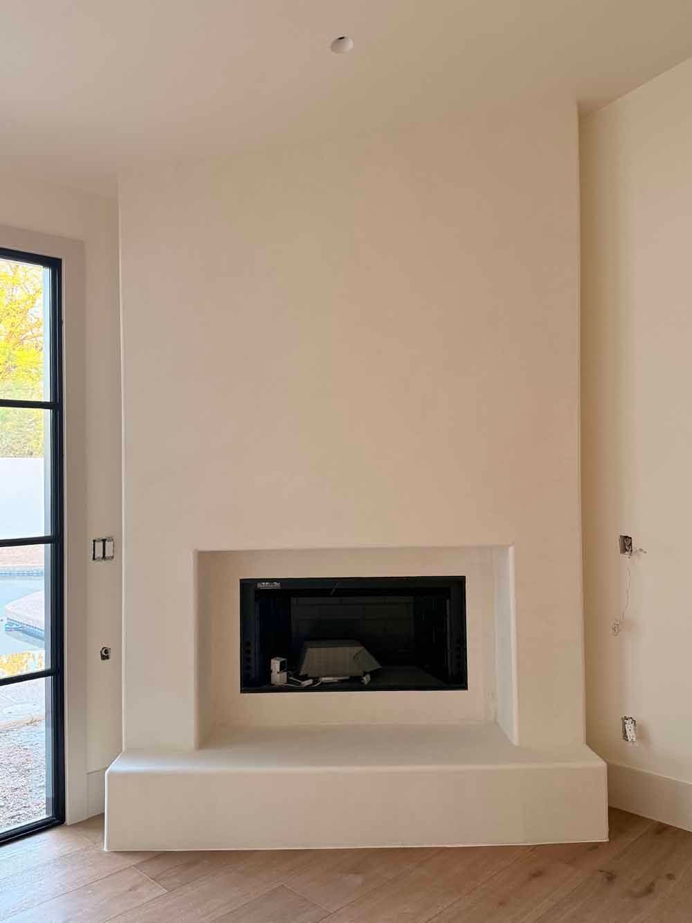 Modern beige room with a built-in black fireplace and a glass door on the left