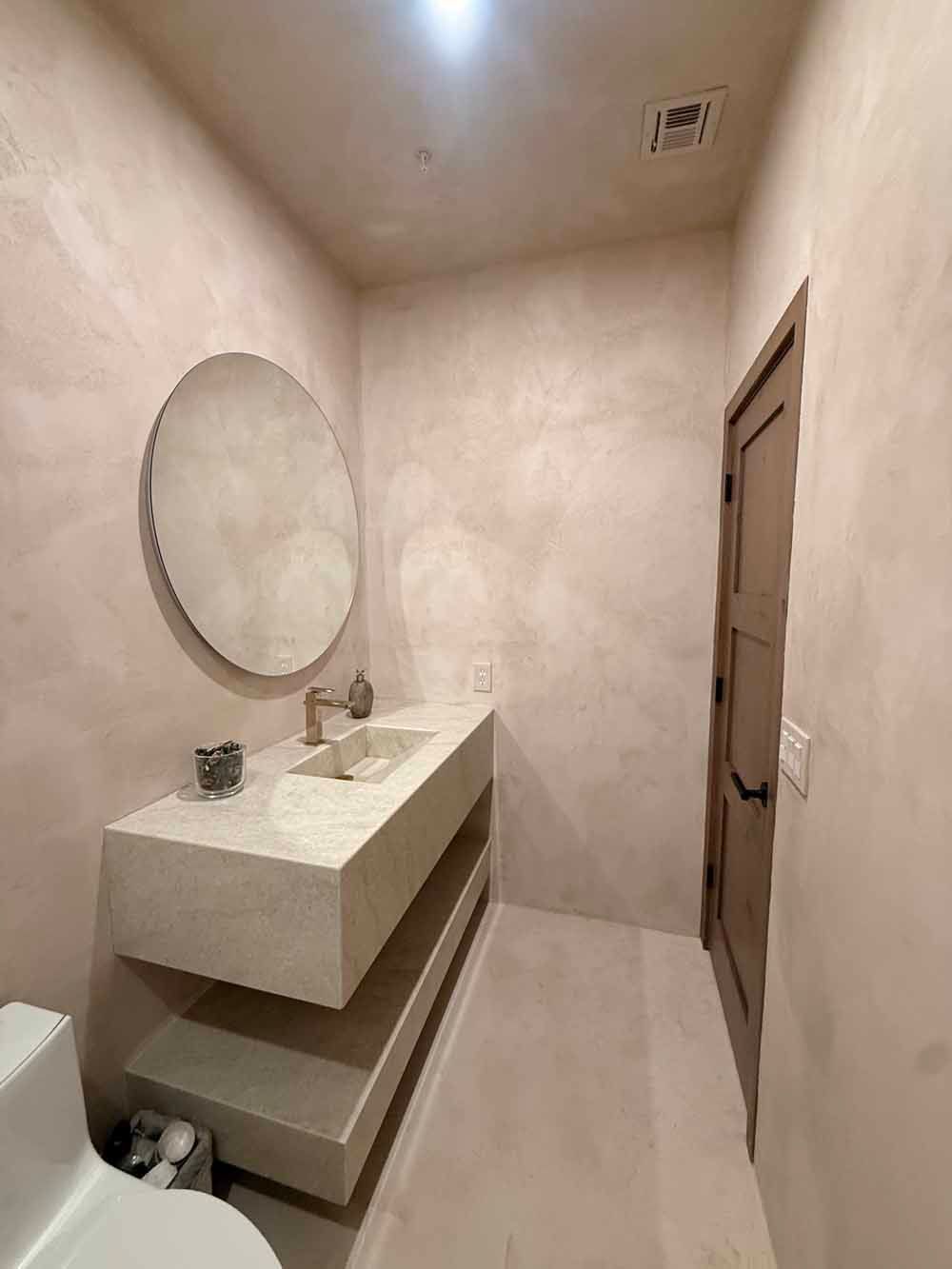 Modern minimalist bathroom with floating sink, round mirror, and beige tile walls