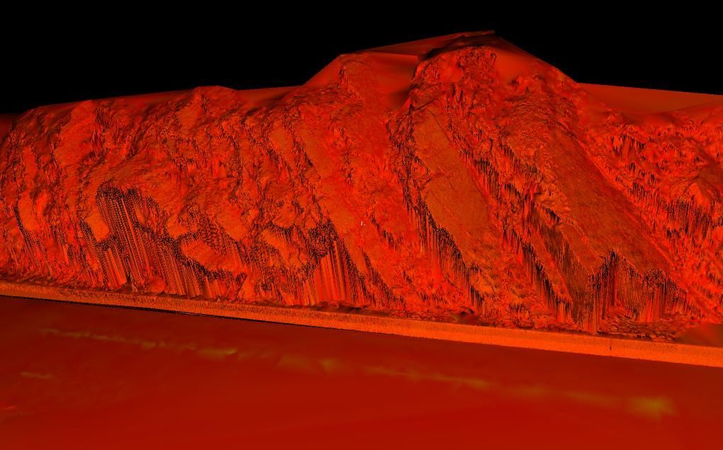 Red-lit mountain ridge reflected in a calm body of water at dusk