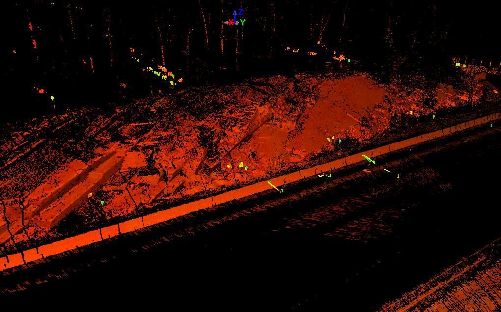 Aerial night view of a dark street with an orange-lit hillside or embankment beside it.
