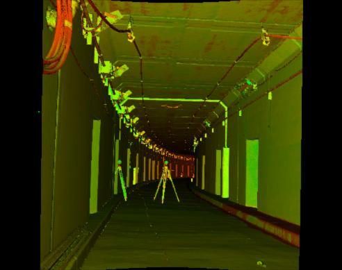 Dim green-lit tunnel with a tripod-mounted device centered on the floor