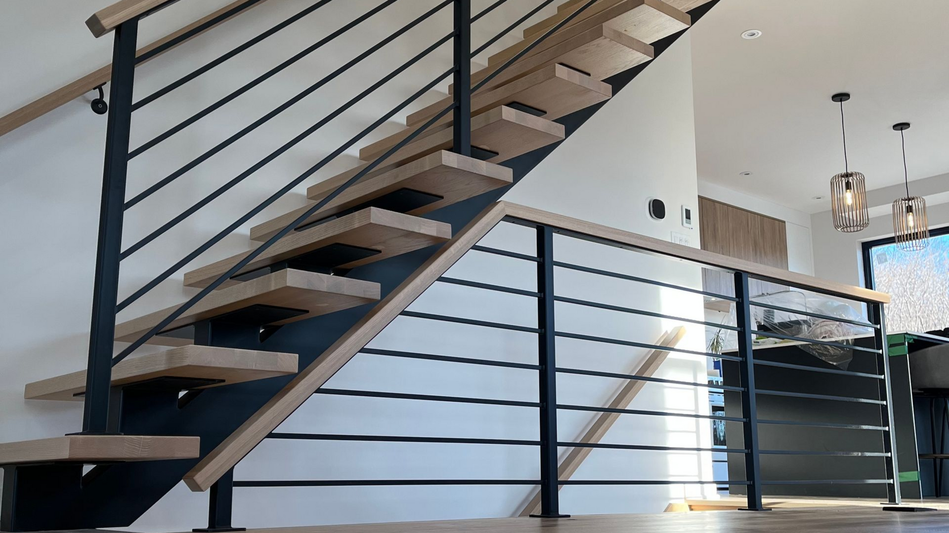 Escalier en bois avec rampes en métal noir dans une maison moderne.