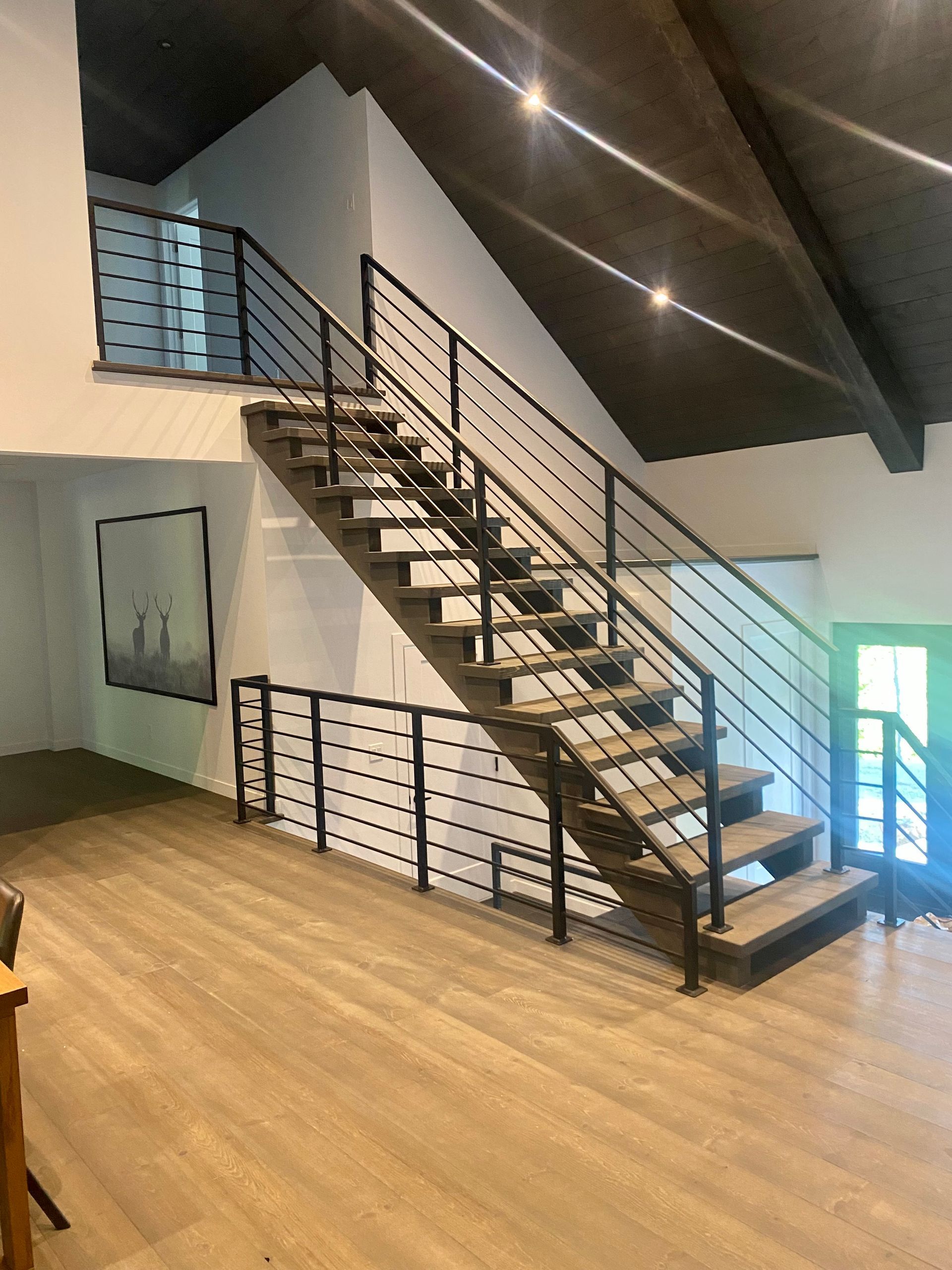 Escalier en bois avec rampes en métal noir dans une maison moderne.