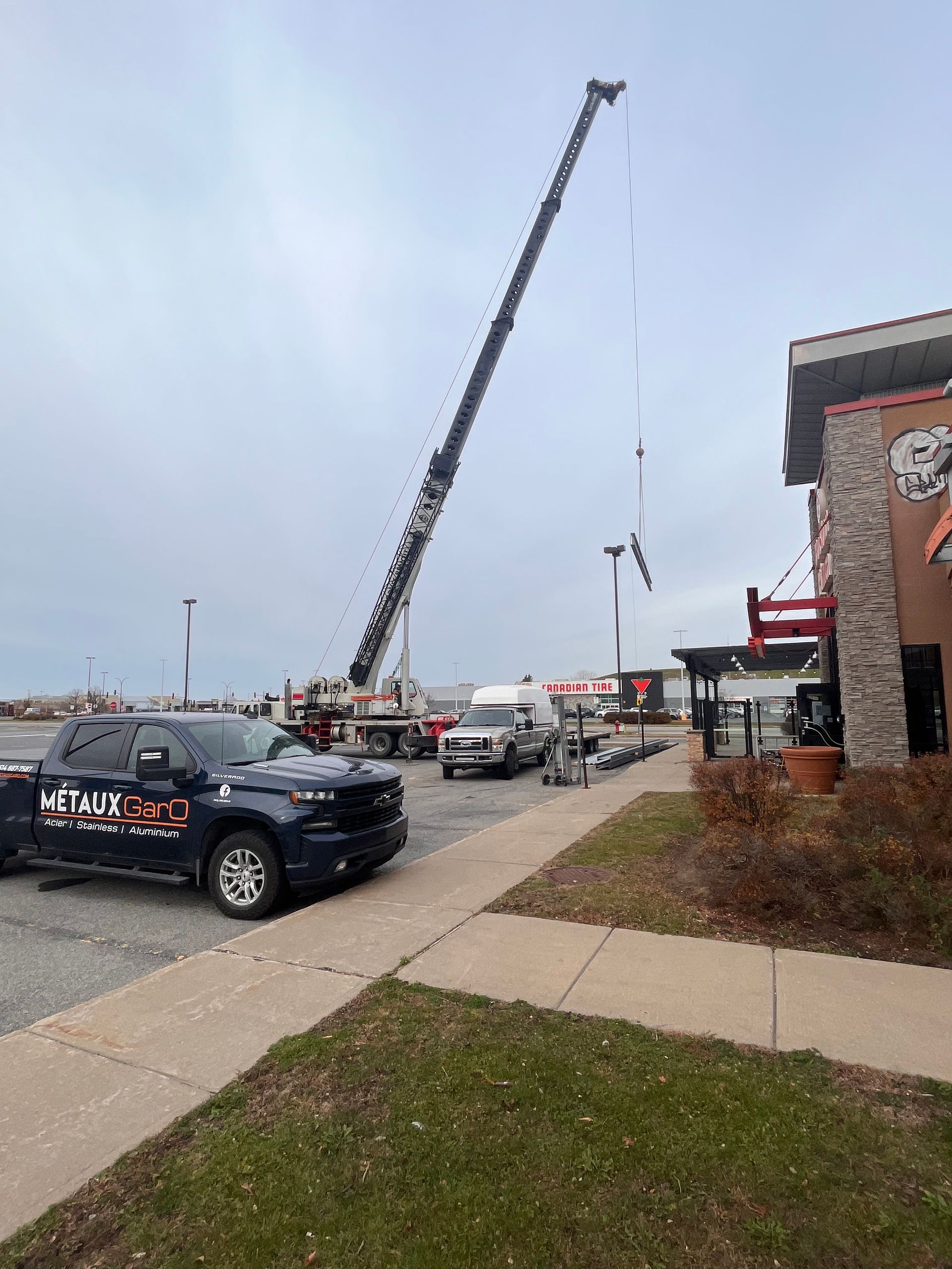 Une grue est installée à côté d'un bâtiment, probablement pour des travaux de réparation. Un camion est stationné à proximité.