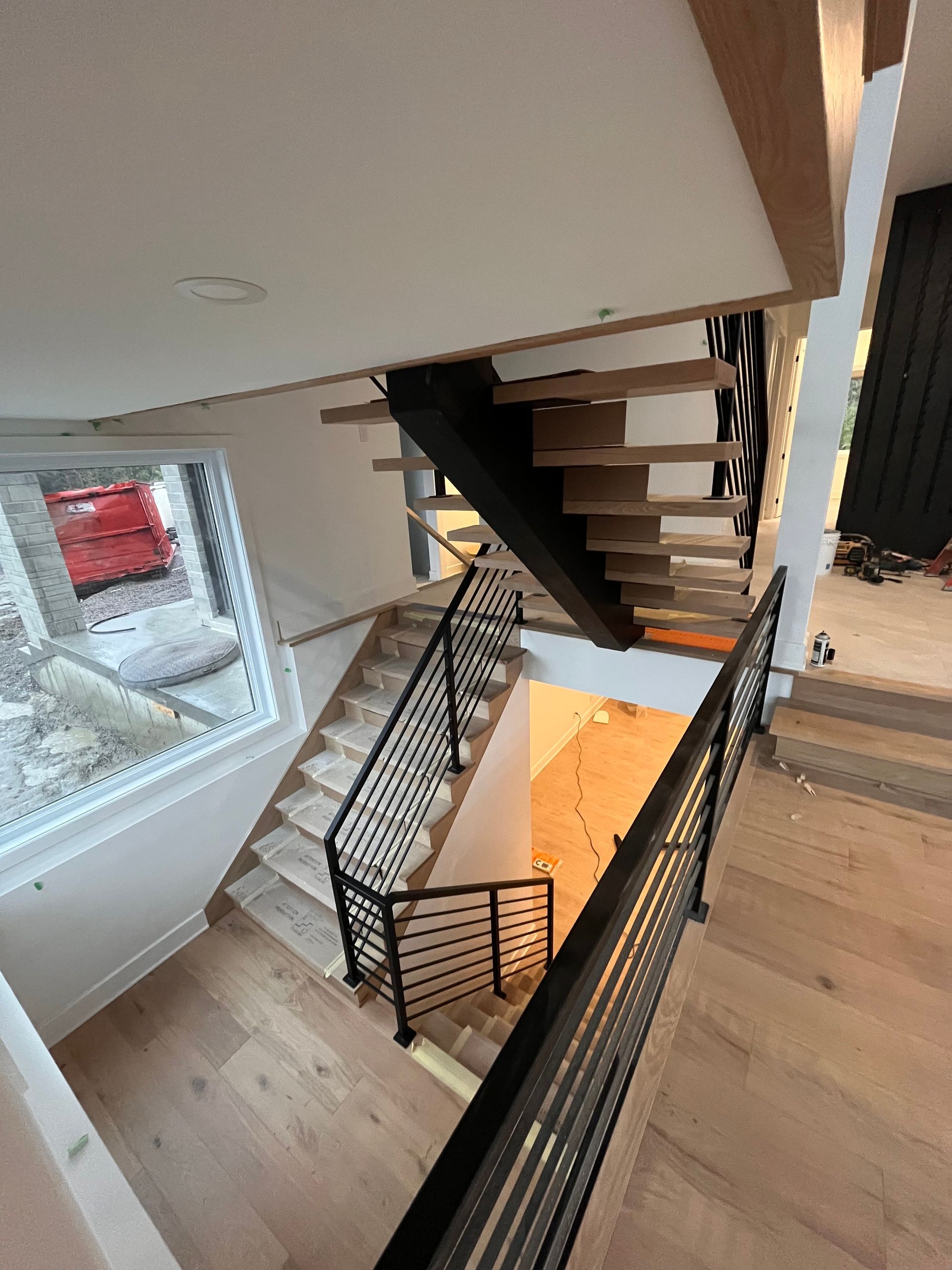 Escalier avec marches en bois et rampes en métal noir dans une maison moderne.