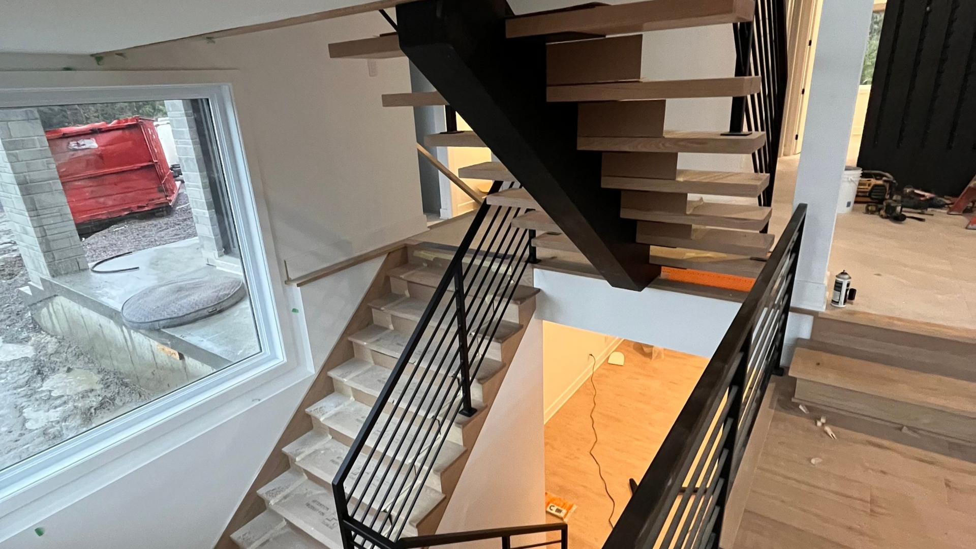 Escalier avec marches en bois et rampes en métal noir dans une maison moderne.