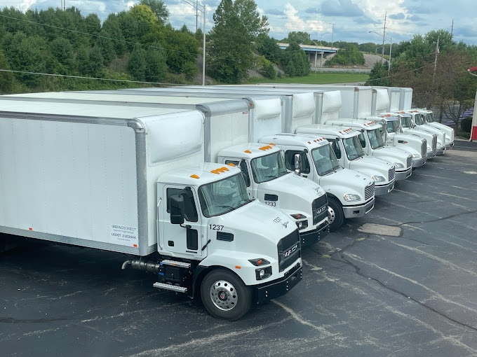 A row of semi trucks are driving down a highway.