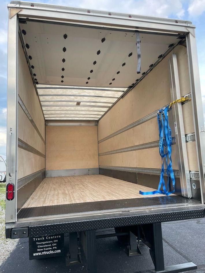 A semi truck is parked in front of a row of shipping containers.