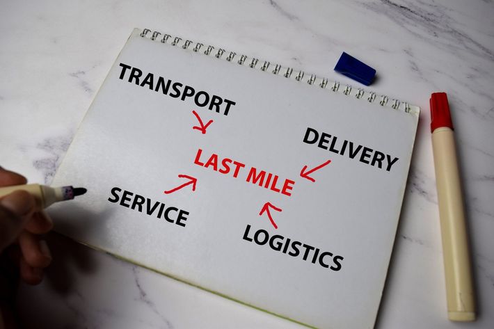A person is writing on a notepad about transport , delivery , last mile , service and logistics.