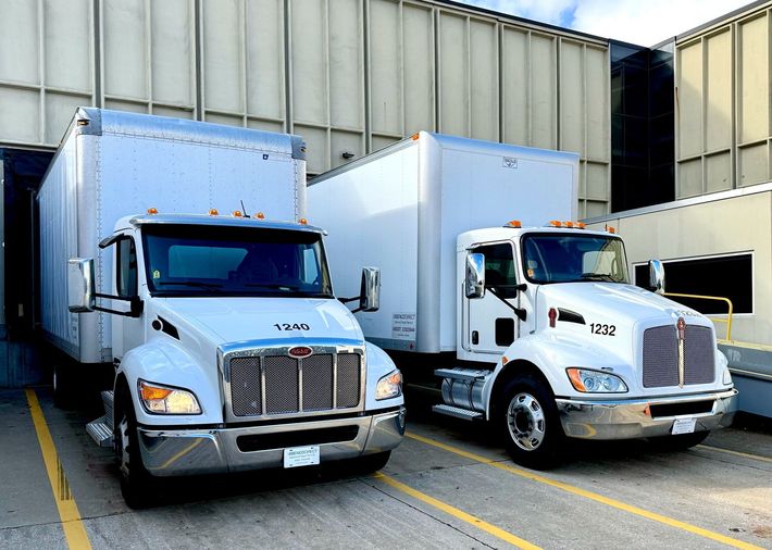 A group of trucks are parked in front of a warehouse.