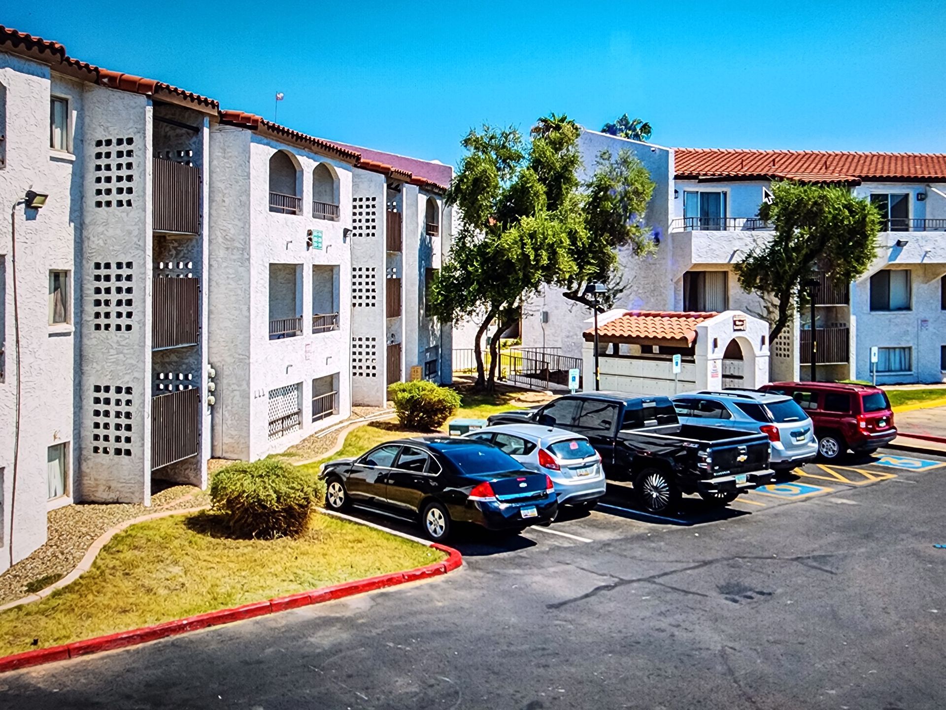 A lot of cars are parked in front of a building.