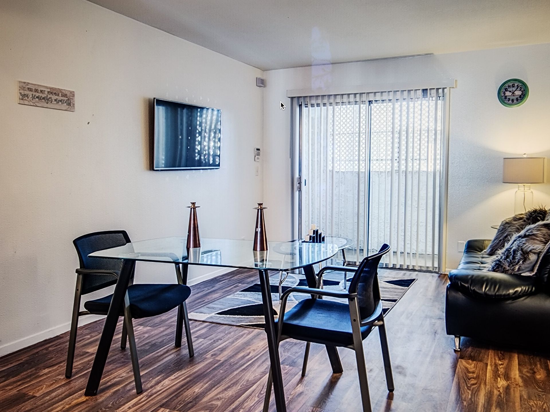 A living room with a dining table , chairs , a couch and a flat screen tv.