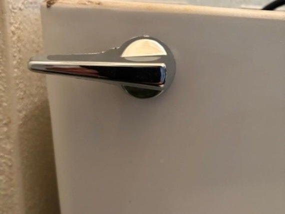 Chrome toilet handle on white tank.