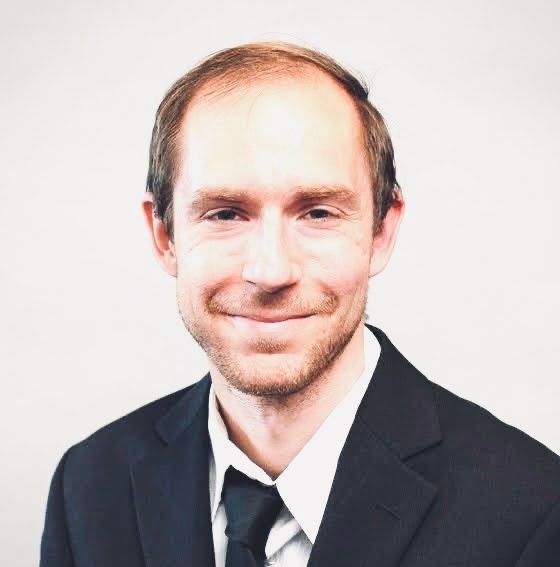 a man in a suit and tie is smiling for the camera .