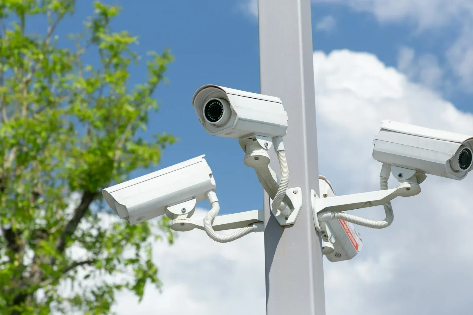 A security camera is hanging from a pole outside of a building.