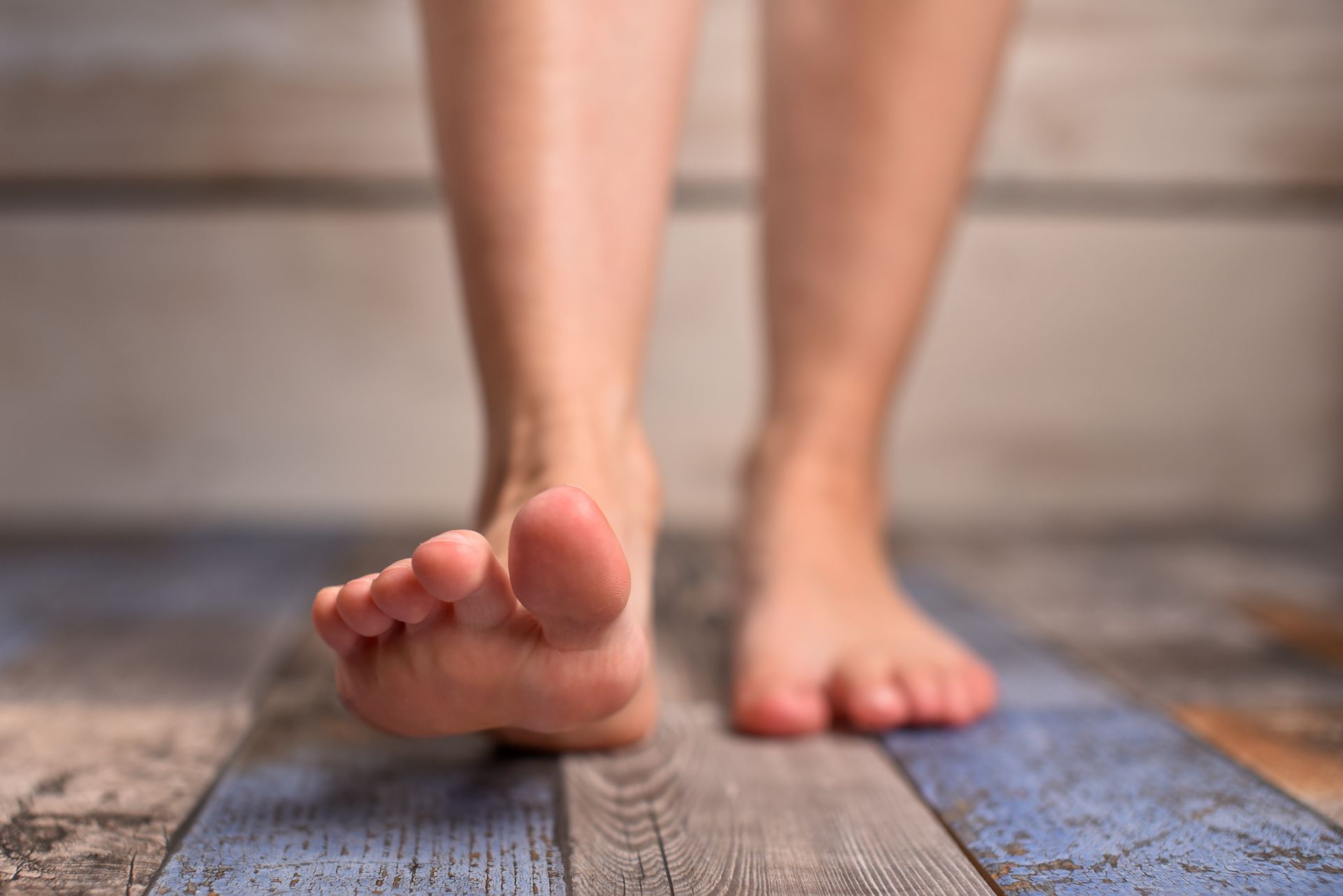 Piedi nudi che camminano in avanti su un pavimento di legno con strisce blu e bianche.