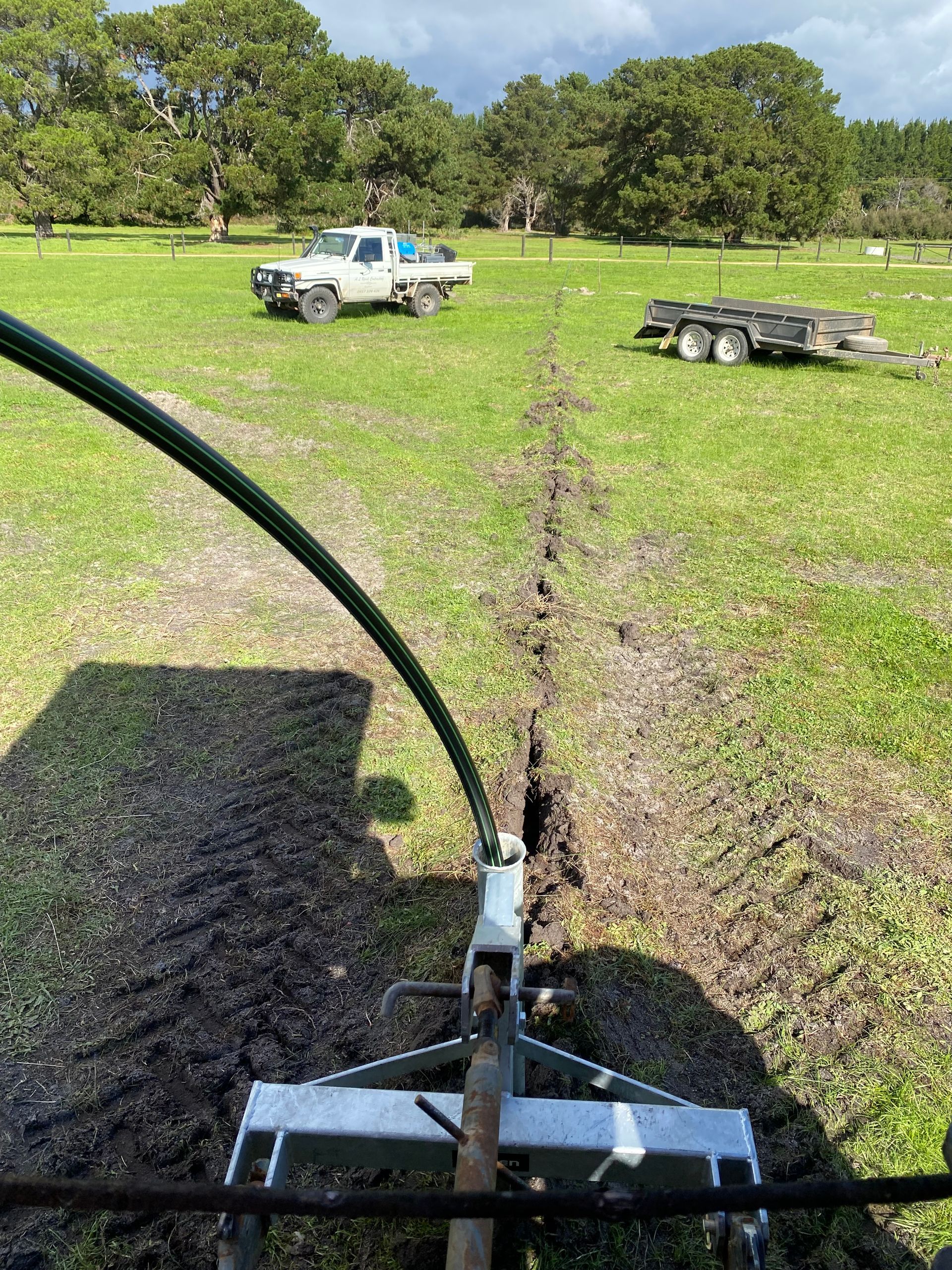 A white truck is parked in a grassy field next to a trailer.