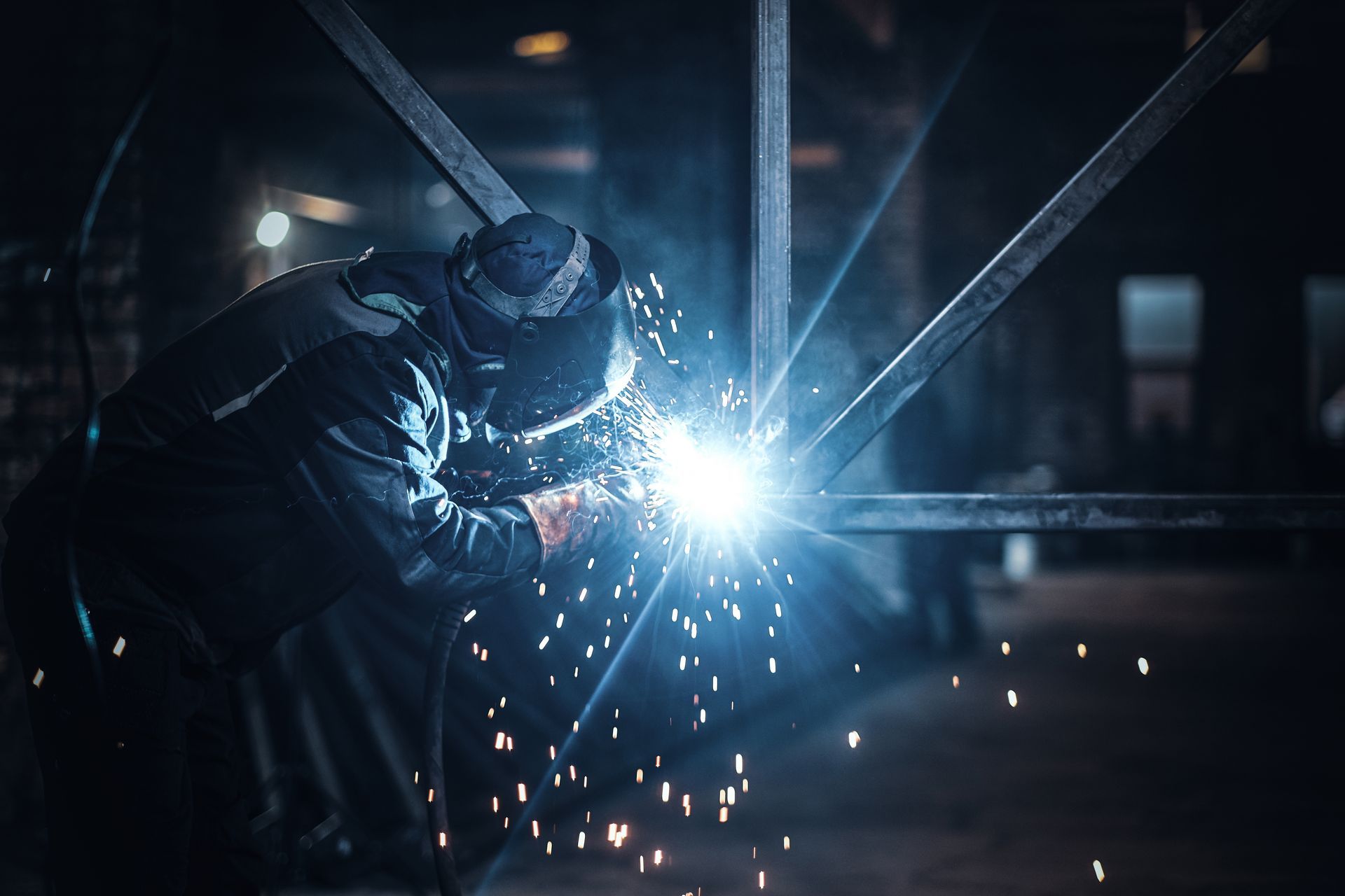 Welder working on a steel structure with bright sparks in a fabrication shop. Welder working on a steel structure with bright sparks in a fabrication shop.