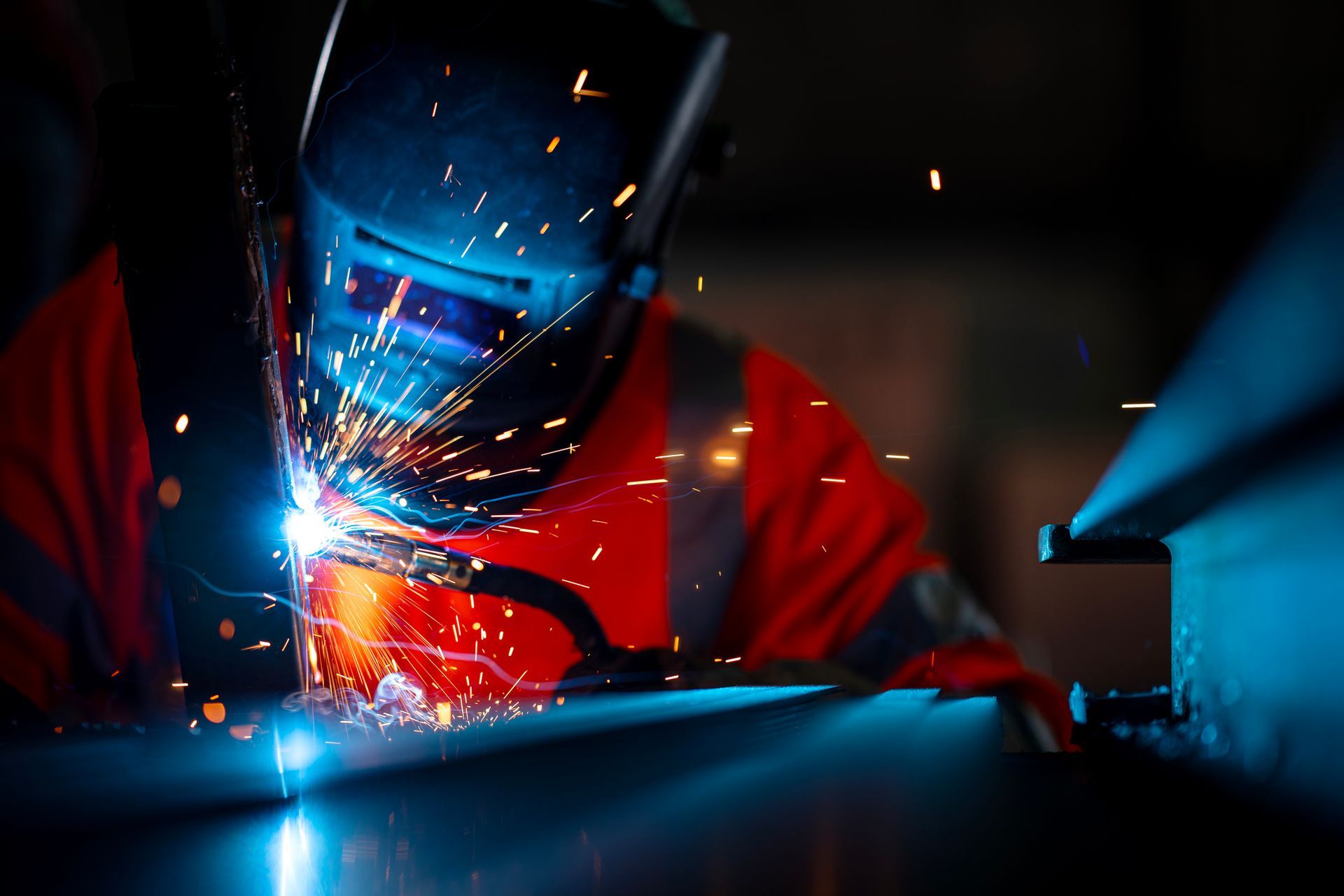 Welding metal with bright sparks and protective gear.
