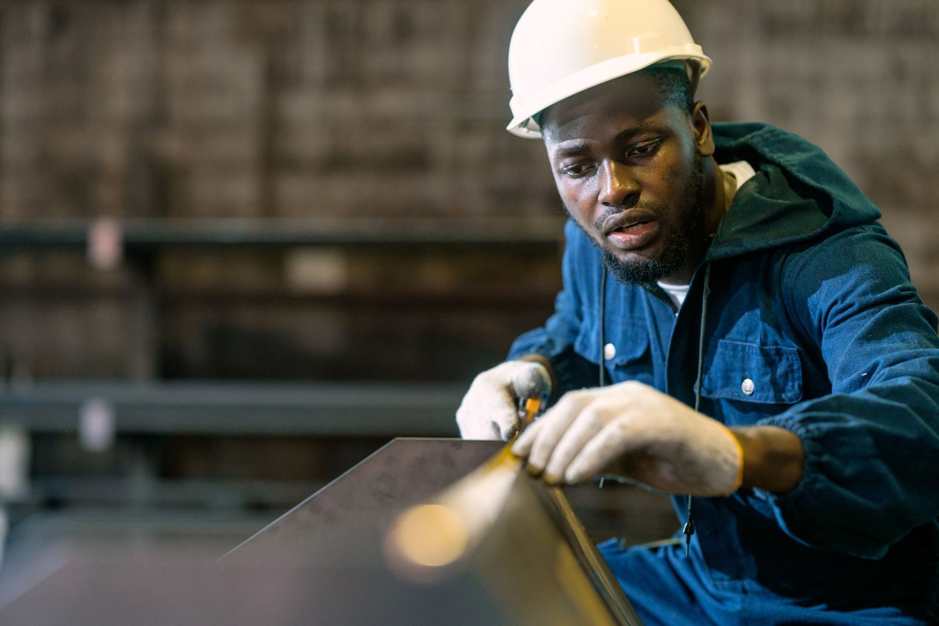 A worker is measuring the length of a piece of steel. A worker is measuring the length of a piece of steel.