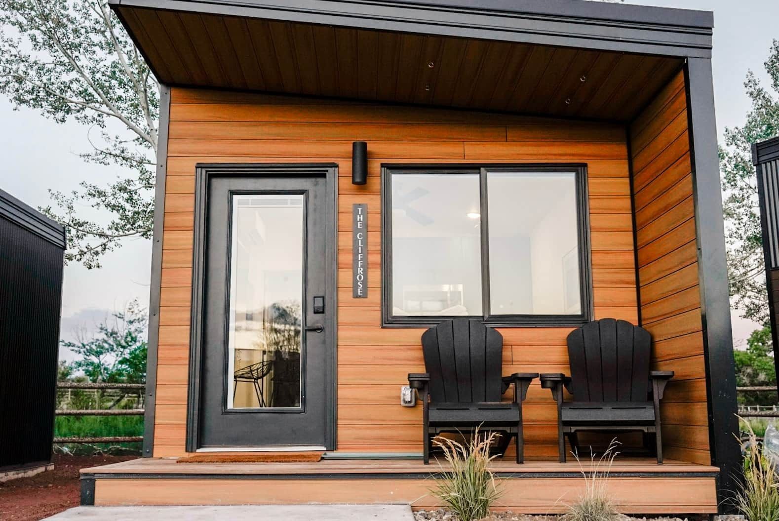 a small wooden house with two chairs on the porch .