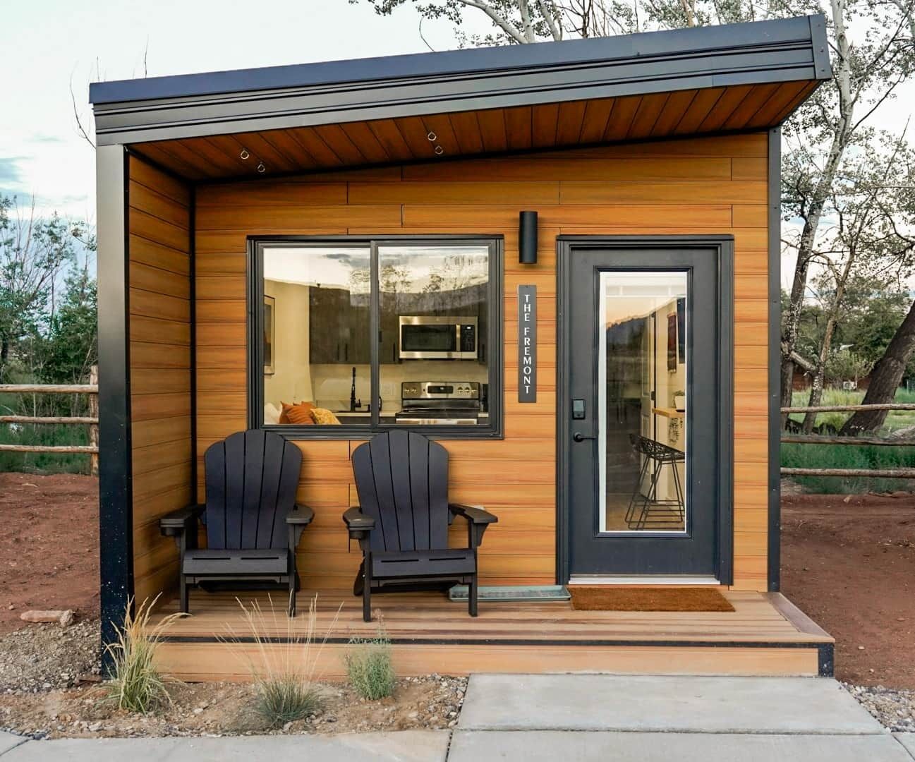 a small wooden house with two chairs in front of it .