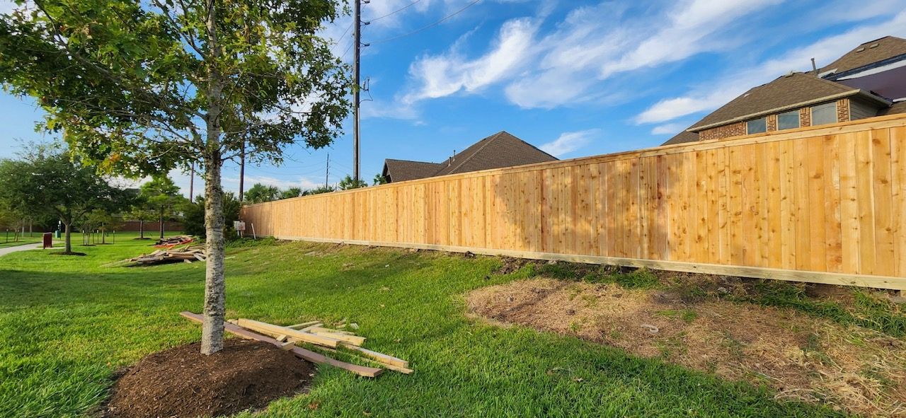 A wooden fence is being built in the backyard of a house.