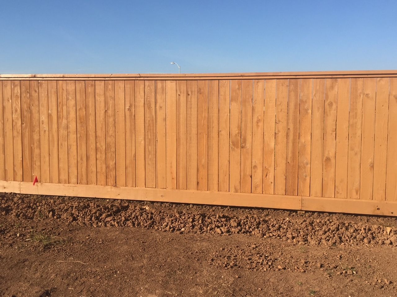 A wooden fence is sitting in the middle of a dirt field.