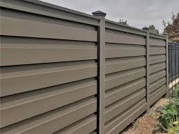 A close up of a wooden fence with a black fence in the background.