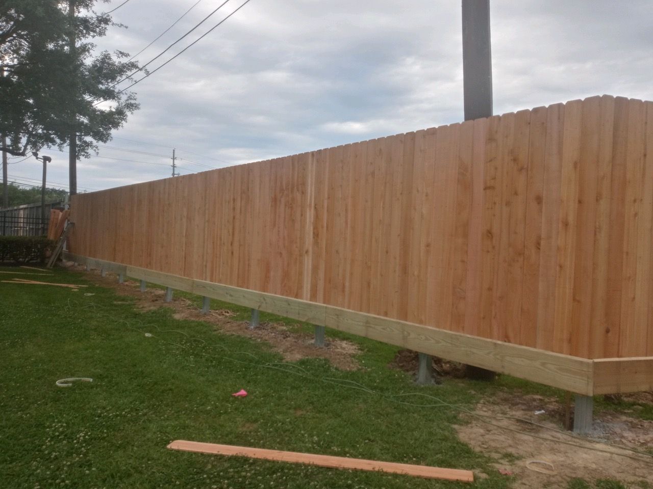 A wooden fence is being built in a backyard.