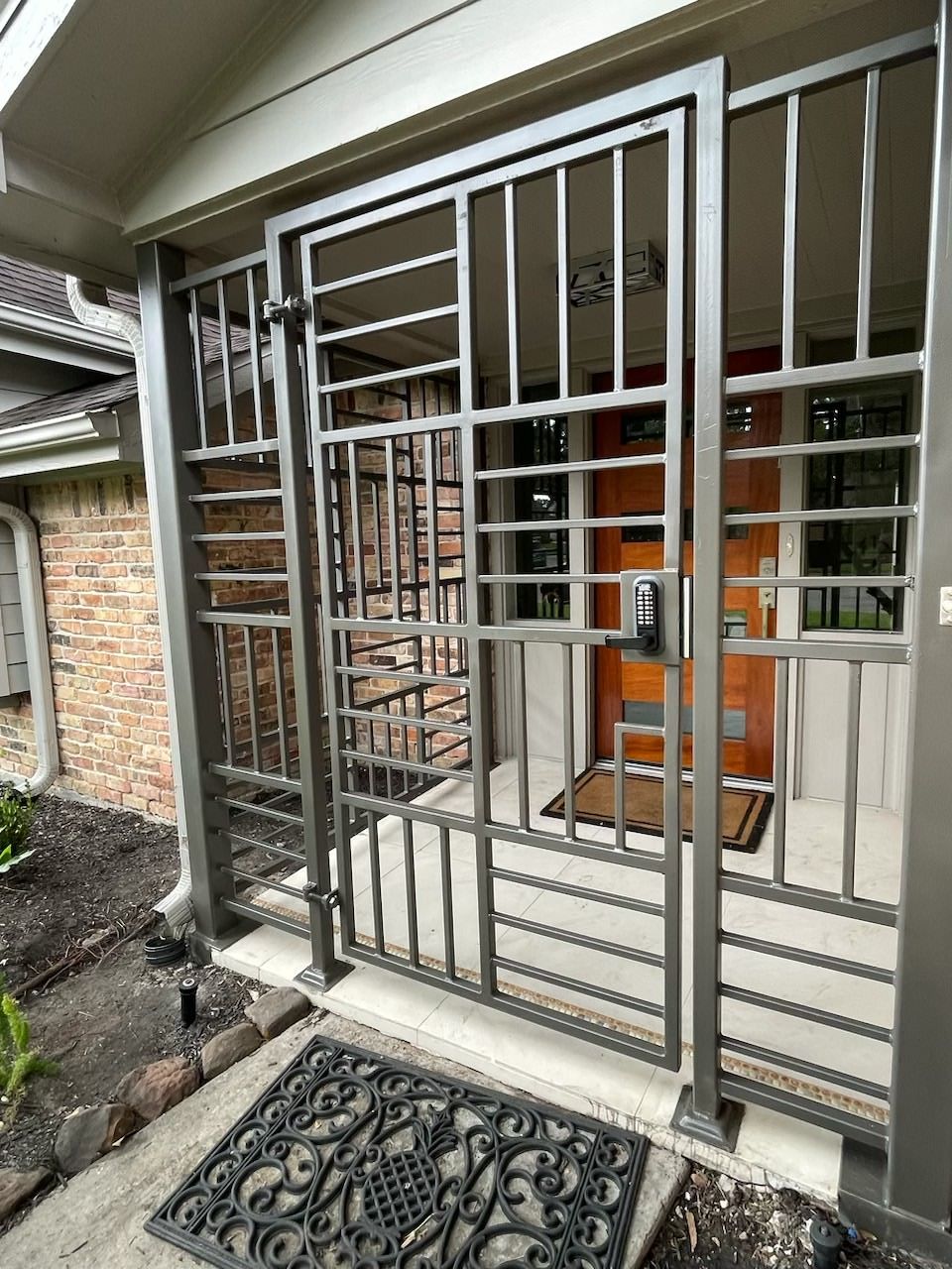 A wrought iron gate is surrounding the front door of a house.