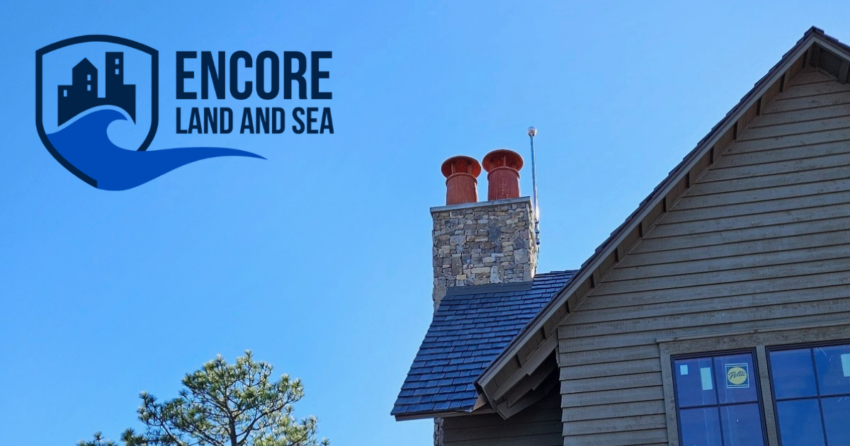 Logo: Encore Land and Sea. A brown house with chimney and blue sky.
