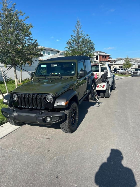 A green jeep is parked next to a white jeep in a parking lot.