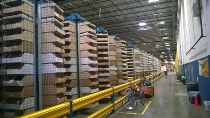 A warehouse filled with lots of cardboard boxes and a bicycle