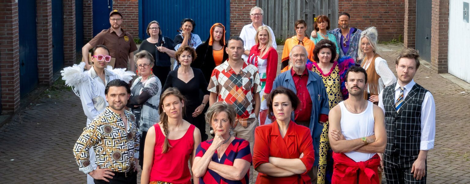 Een groep mensen poseert buiten; ze dragen diverse kleurrijke outfits.