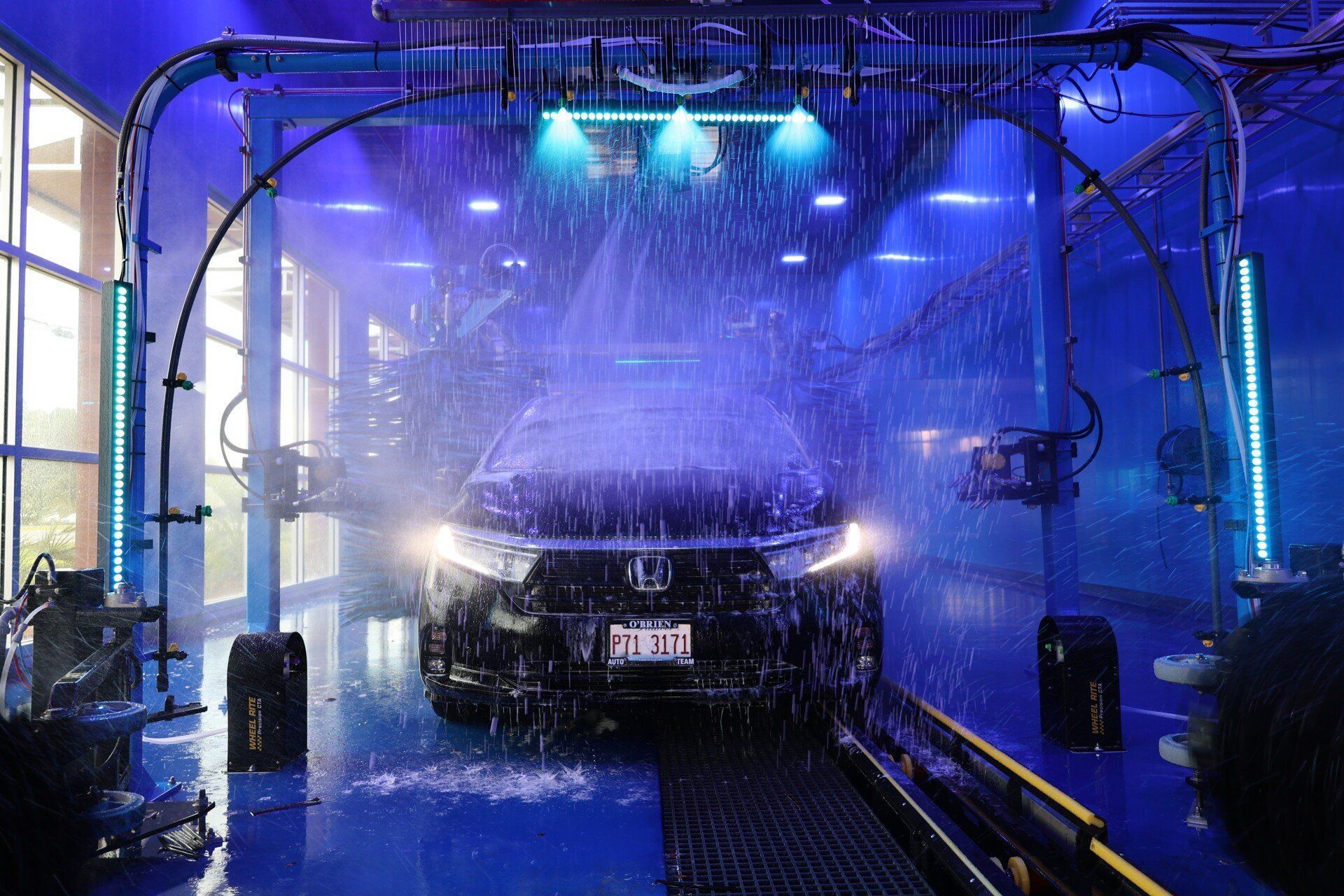 Car wash under blue lights in an automated car wash, water spraying over the vehicle